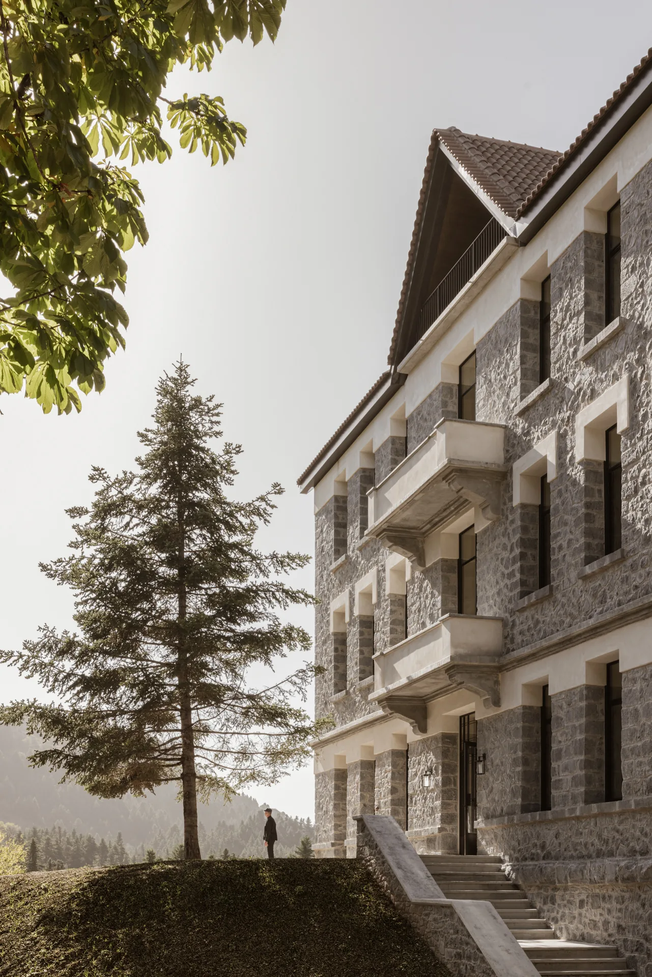MANNA's historic stone exterior among the autumn forest of Mount Mainalo