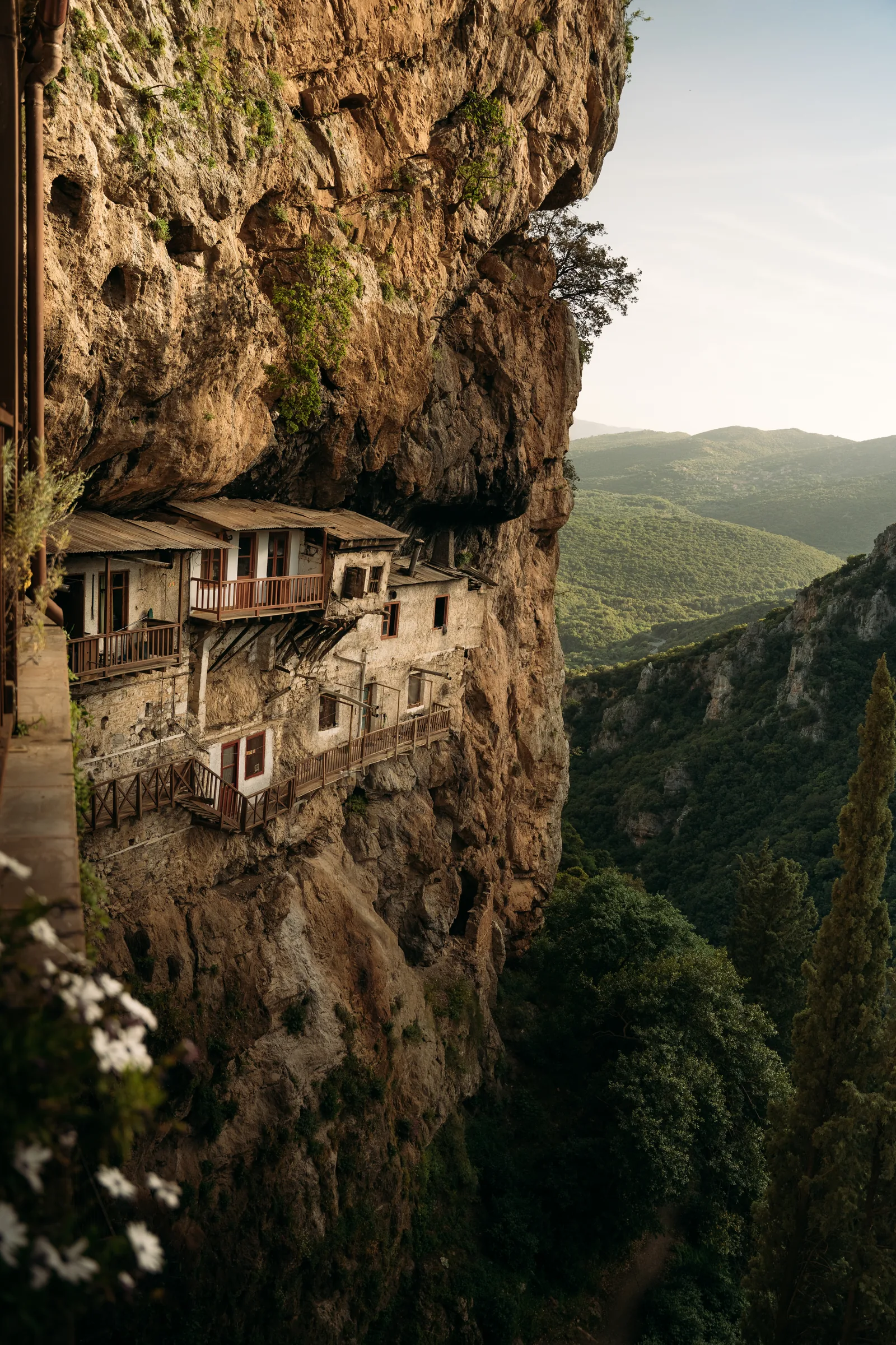 The Monastery of St John the Baptist beneath an overhanging cliff, overlooking the wooded Lousios Gorge