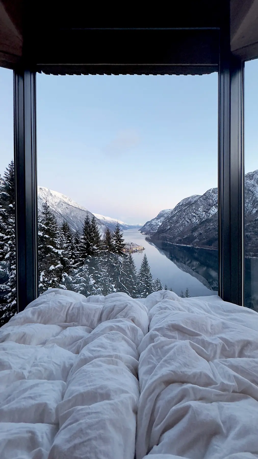 View from the Woodnest bed across snow-covered forest to the Hardangerfjord